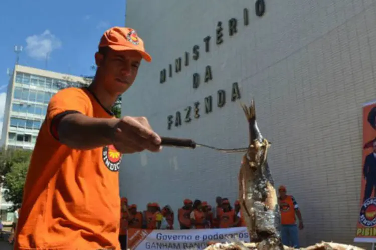 Integrante da Força Sindical assa sardinha durante protesto: trabalhadores trouxeram mais de 40 quilos do peixe e 30 abacaxis (Marcello Casal Jr./ABr)