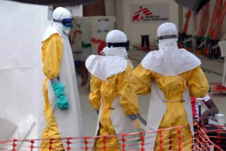 Profissionais de saúde usando roupa protetora são vistos no centro de atendimento ao ebola (Zoom Dosso/AFP)