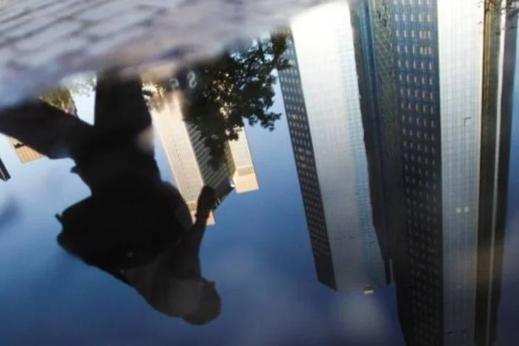 
	Sede do Deutsche Bank refletida em uma po&ccedil;a d&#39;&aacute;gua em Frankfurt, Alemanha: apesar disso, a institui&ccedil;&atilde;o aumentou sua meta de cortes de empregos
 (Alex Domanski/Reuters)