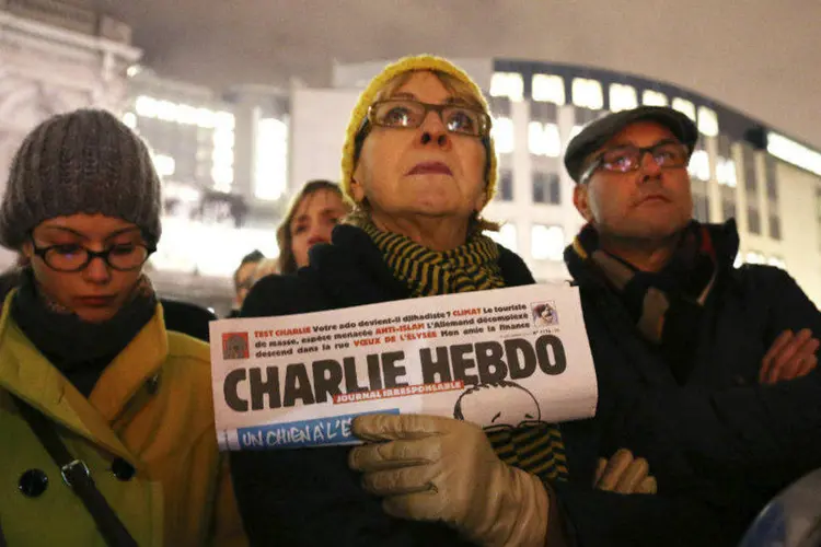 Mulher segura cópia de tributo às vítimas do ataque contra a sede da revista Charlie Hebdo (Francois Lenoir/Reuters)