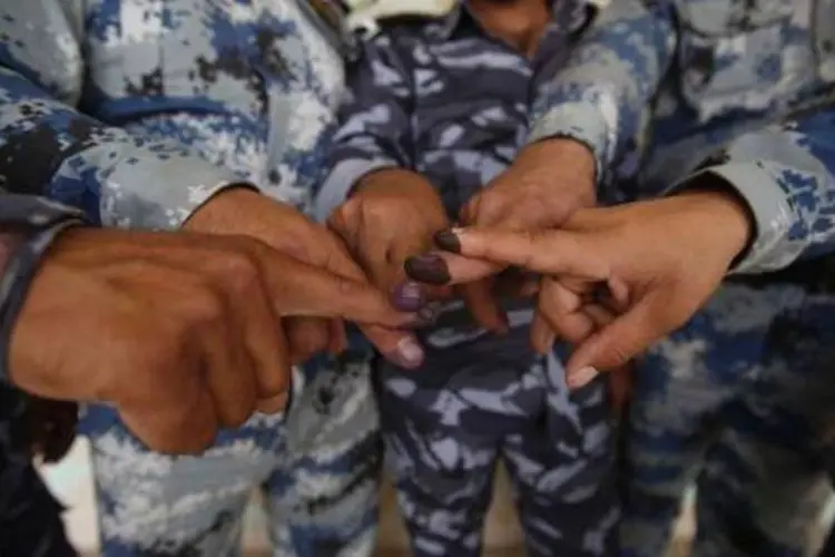 Membros das forças de segurança exibem os dedos sujos de tinta após votarem:  ataque mais violento foi registrado em um centro eleitoral a oeste de Bagdá (Mohammed Sawaf/AFP)