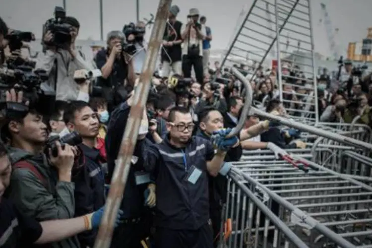 Agentes de segurança retiram barricada em prédio próximo da área de protestos em Hong Kong (Philippe Lopez/AFP)