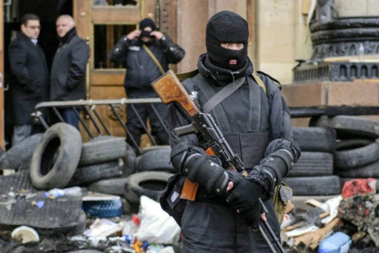 Homem mascarado e armado das forças especiais ucranianas fica de guarda em frente ao prédio da administração regional de Kharkiv (Olga Ivashchenko/Reuters)