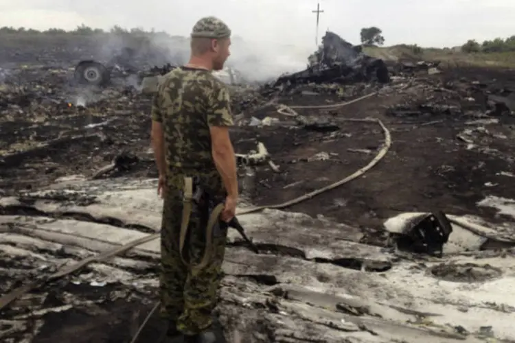 
	Rebelde pr&oacute;-R&uacute;ssia observa local onde aeronave caiu, em &aacute;rea sob controle de separatistas
 (Maxim Zmeyev/Reuters)