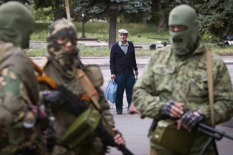 Homem observa separatistas armados pró-Rússia em Snizhnye, no leste da Ucrânia (Shamil Zhumatov/Reuters)