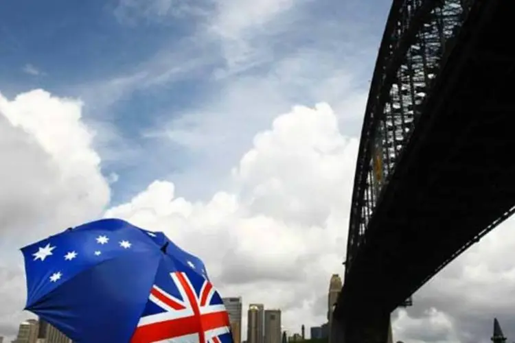 
	Pessoa segura guarda-chuva com estampa da bandeira australiana em Sydney, Austr&aacute;lia:&nbsp;Tesouro prev&ecirc; que a receita tribut&aacute;ria caia em cerca de 4 bilh&otilde;es
 (Brendon Thorne/Getty Images)