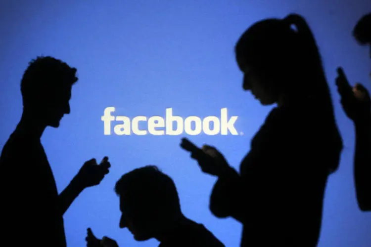 
	Silhueta de pessoas mexendo em smartphones em frente a logo do Facebook
 (Dado Ruvic/Files/Reuters)