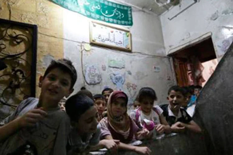
	Crian&ccedil;as s&iacute;rias no primeiro dia de aula em uma escola em uma &aacute;rea dominada por insurgentes na cidade de Alepo
 (Zein al-Rifai/AFP)
