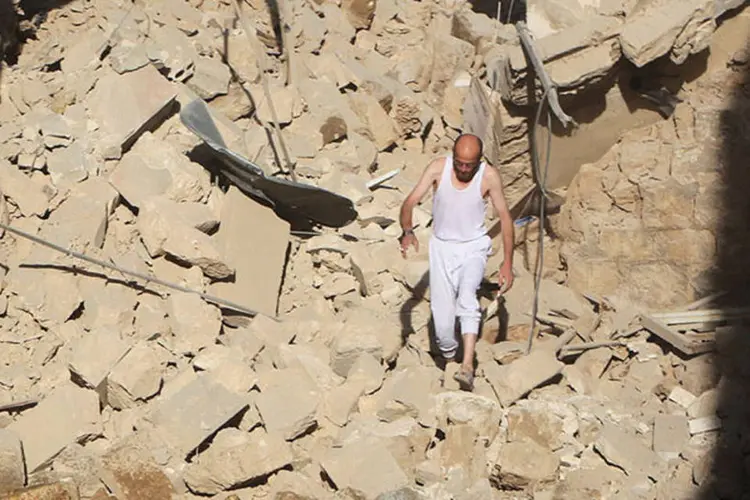 Homem caminha por destroços de prédio na Síria: os jihadistas intensificaram ontem o disparo de foguetes  (REUTERS/Mahmoud Hebbo)
