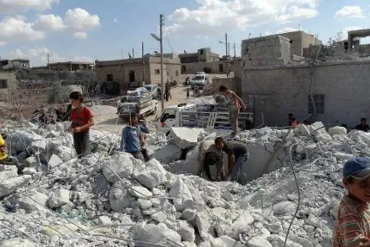 Sírios em meio aos escombros após ataque da coalizão internacional (Sami Ali/AFP)