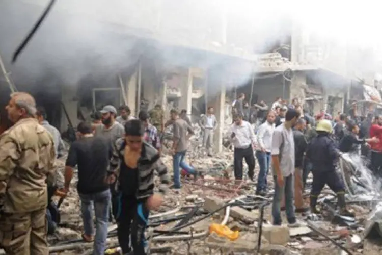 
	Pessoas observam destro&ccedil;os ap&oacute;s ataque com carro-bomba na segunda-feira em Mazzeh: local &eacute; t&atilde;o importante quanto aeroporto internacional de Damasco, segundo OSDH
 (Sana/AFP)