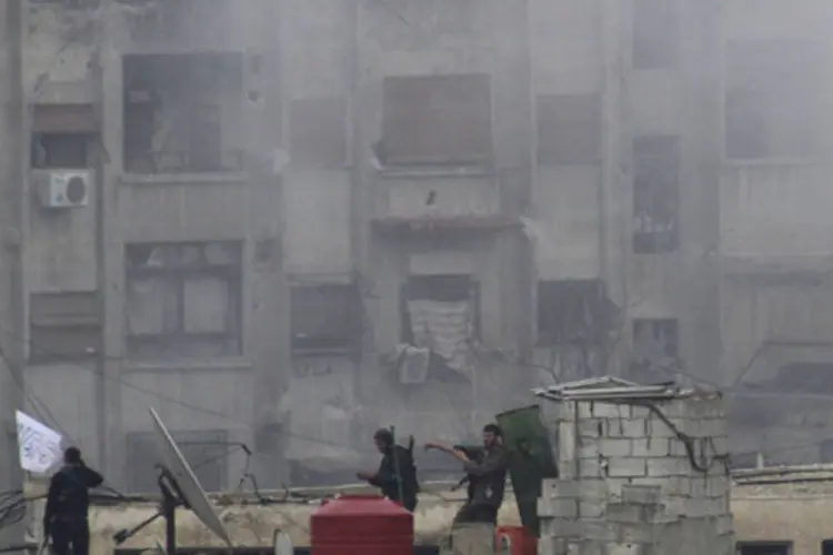 Integrantes do Exército Sírio Livre levantam bandeira islâmica no topo de um prédio em Damasco: nenhum grupo assumiu a responsabilidade do ataque em uma fábrica militar (Mohamed Dimashkia/Reuters)