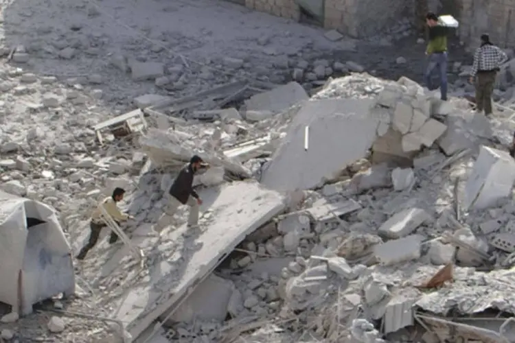
	Moradores e membros do Ex&eacute;rcito S&iacute;rio Livre caminham sobre escombros de pr&eacute;dio perto de Idlib:&nbsp;bombardeios das tropas governamentais atingiram a cidade de Telmens, em Idlib
 (Reuters/Abu Qais al-Taftanazi/Shaam News Network/Divulgação)