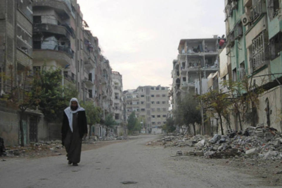 
	Um homem caminha por uma rua destru&iacute;da em Duma, bairro de Damasco, na S&iacute;ria
 (Reuters/William Ismail)