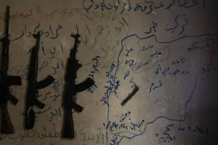 
	Armas s&atilde;o vistas ao lado de mapa da S&iacute;ria desenhado na parede de casa de rebeldes em Alepo
 (REUTERS/Muzaffar Salman)