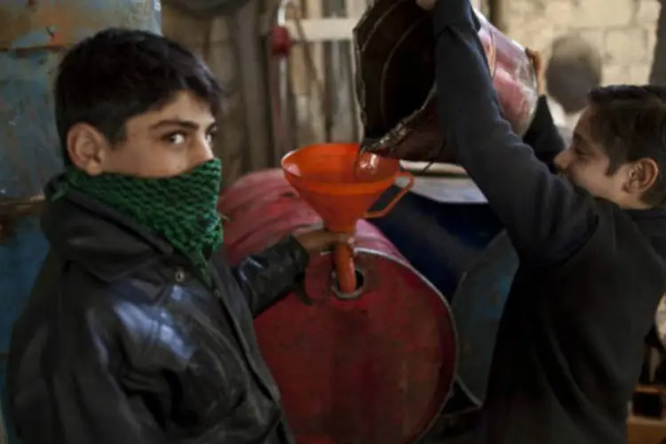 Jovens sírios enchem barris com combustível na cidade de Azaz: as forças de Assad tomaram neste sábado um distrito na cidade de Homs (©afp.com)