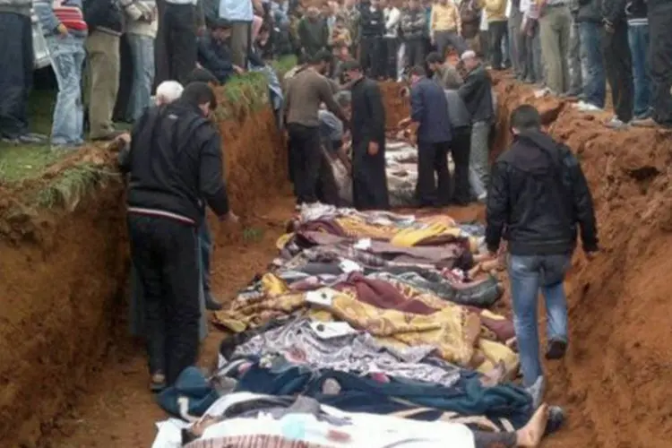 Sírios observam cova coletiva em Taftnaz (AFP)
