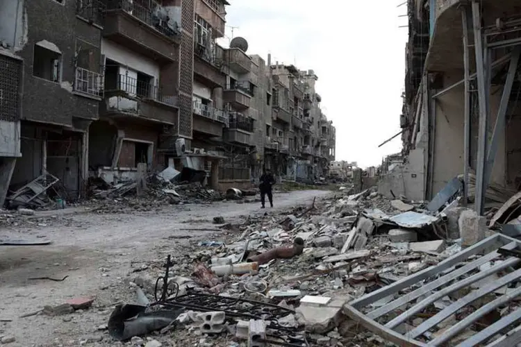 
	Soldado anda em frente a pr&eacute;dios destru&iacute;dos na S&iacute;ria
 (REUTERS/Bassam Khabieh)