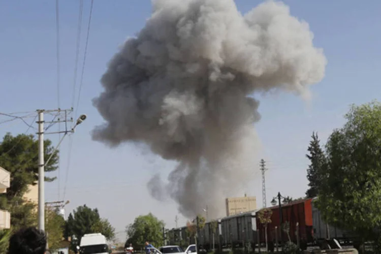 Coluna de fumaça é vista da fronteira turca na cidade de Ras al-Ain, na Síria, após ataque aéreo (Murad Sezer/Reuters)