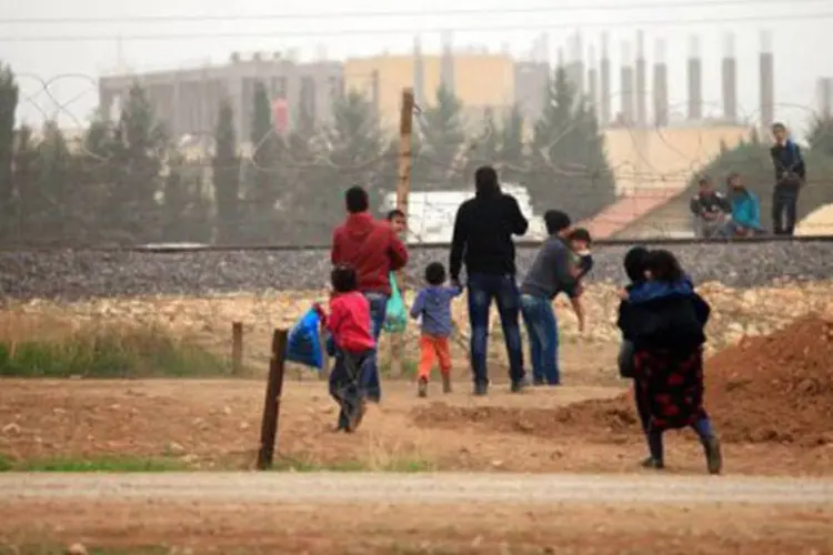 Família de refugiados cruza a fronteira com a Turquia: diariamente, aproximadamente 2.000 refugiados sírios se deslocam


 (AFP)