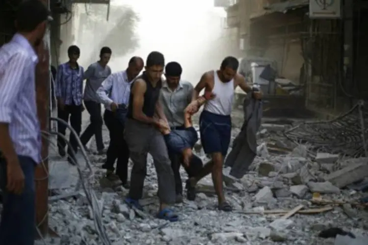 Sírios removem um homem ferido em ataques aéreos atribuídos a forças do governo sírio (Samir Al-Dumy/AFP)