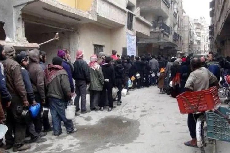 Sírios fazem fila para receber comida, em um campo de refugiados localizado nos arredores de Damasco (Rami al-Sayed/AFP)