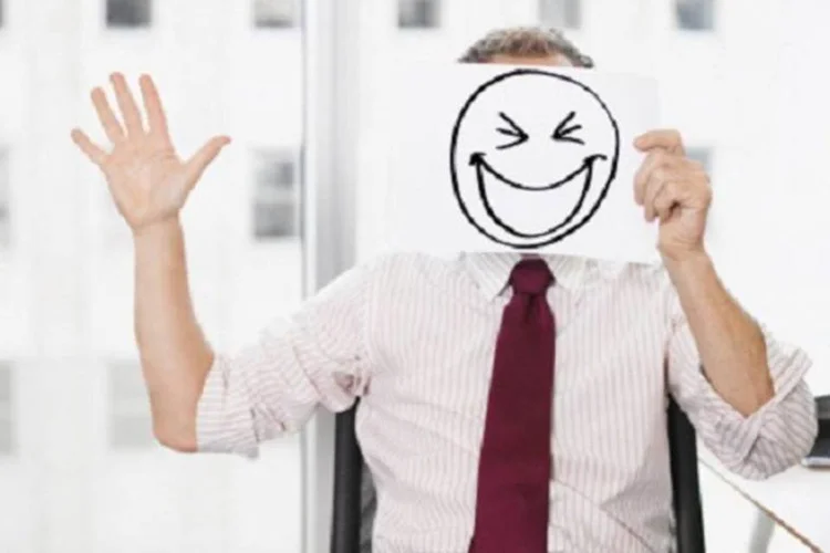 Executivo segura desenho de um sorriso no rosto (Getty Images)