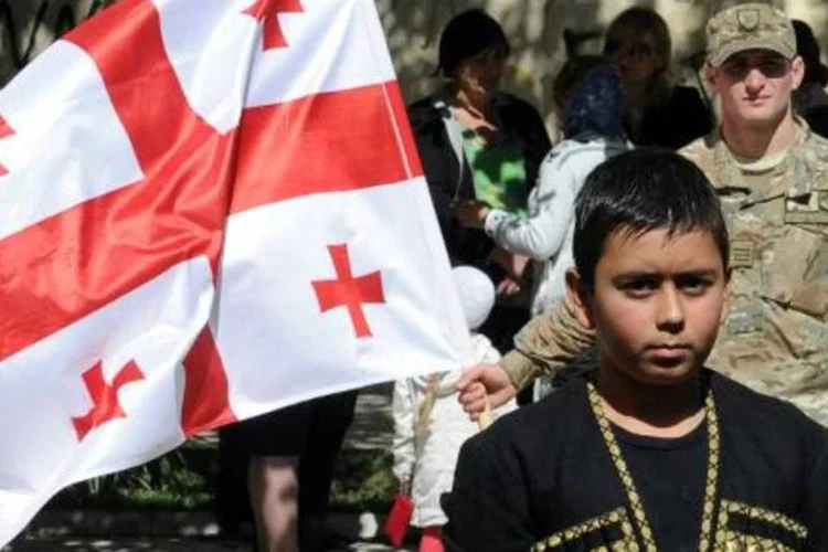 Soldado georgiano segura bandeira nacional durante comemoração do 21º aniversário da retirada de tropas georgianas da cidade de Abkházia (Vano Shlamov/AFP)