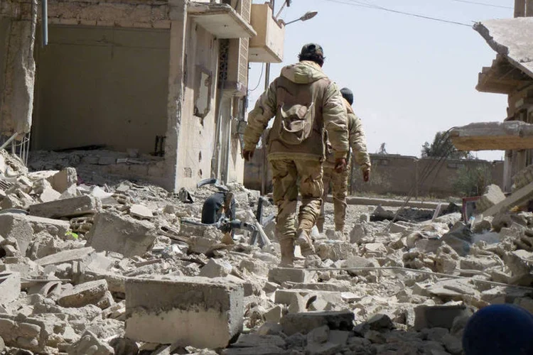 
	Soldado s&iacute;rio andando nos destro&ccedil;os de Palmira p&oacute;s ataque do EI: McGurk disse que os esfor&ccedil;os da coaliz&atilde;o para capturar Mosul e Raqqa est&atilde;o tendo progresso
 (Maher Al Mounes / AFP)