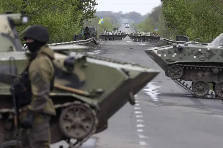 Soldado ucraniano faz guarda em frente a tanques blindados em um posto de controle perto do vilarejo de Malinivka, a sudeste de Slaviansk, no leste da Ucrânia (Baz Ratner/Reuters)