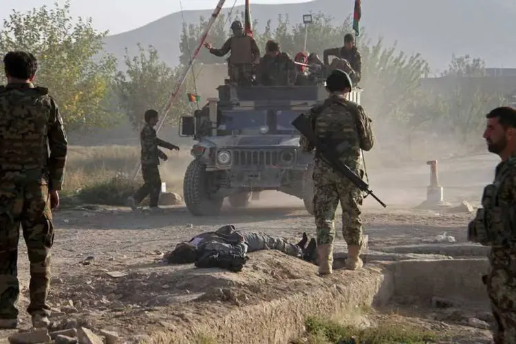 
	Soldados afeg&atilde;os fazem vigia ao lado de corpo de insurgente taleb&atilde;: quatro homens do Taliban e quatro integrantes das for&ccedil;as de seguran&ccedil;a morreram
 (REUTERS/Stringer)