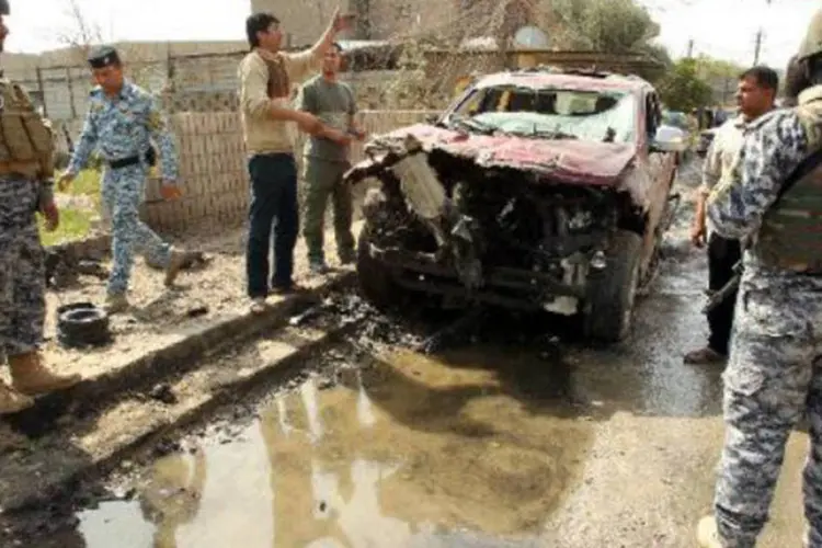 Soldados iraquianos e civis observam área de ataque com carro-bomba: mais de 60 pessoas ficaram feridas (Ali al-Saadi/AFP)