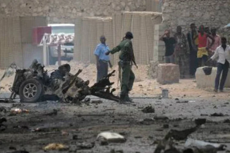 Soldados somalis ao redor de destroços de carro momentos após sua explosão: "motivo do ataque não está claro", disse funcionário de seguraça (Mohamed Abdiwahab/AFP)