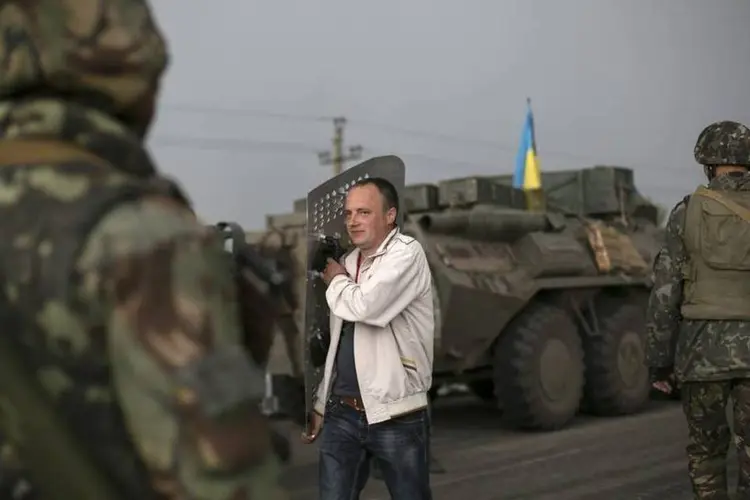 
	Civil passa por soldados ucranianos em uma base militar pr&oacute;xima da cidade de Slaviansk:&nbsp;opera&ccedil;&atilde;o come&ccedil;ou em meados de abril
 (Baz Ratner/Reuters)