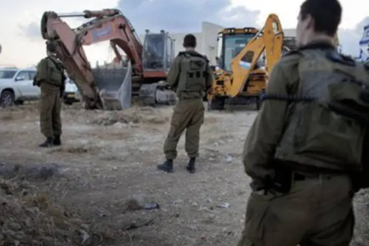 
	Soldados israelenses observam as obras em um assentamento
 (©AFP/File / Marco Longari)