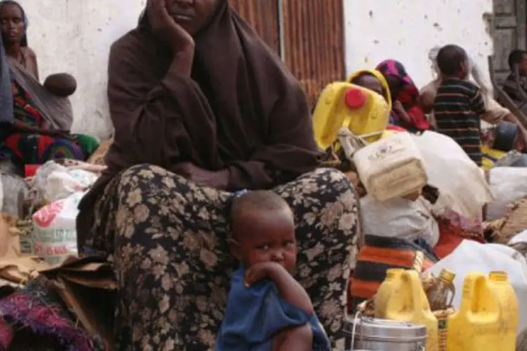 Uma mulher espera ao lado de seu pequeno filho pela distribuição de comida e água: a região do Chifre da África está imersa em uma grave crise humanitária por causa da seca (Mustafa Abdi/AFP)