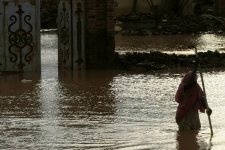 Mulher que teve casa destruída por enchente caminha sobre área alagada no Sudão (REUTERS/Mohamed Nureldin Abdallah)