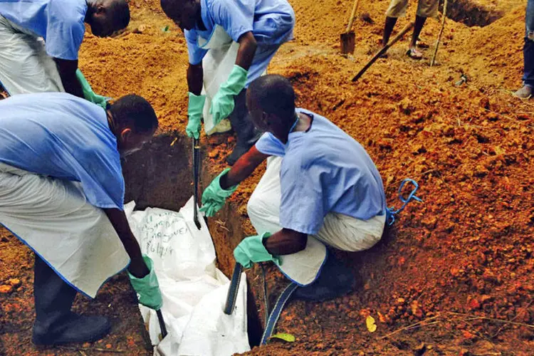 
	Volunt&aacute;rios enterram o corpo de uma das v&iacute;timas do surto de ebola, em Kailahun
 (WHO/Tarik Jasarevic/Divulgação via Reuters)