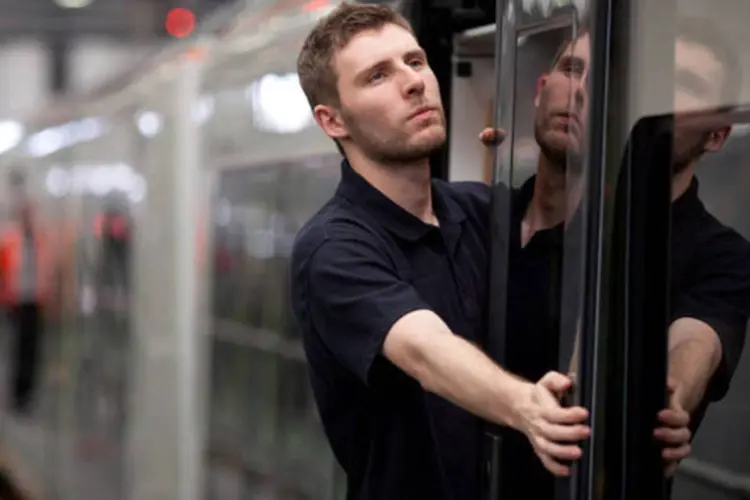 Técnico de manutenção inspeciona a porta de passageiros de um trem da Siemens em uma instalação da companhia no Reino Unidos (Jason Alden/Bloomberg)