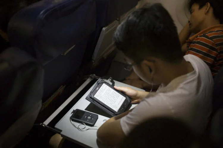 Passageiro lê em tablet a bordo de avião: “as revistas de bordo são dinossauros vivos impressos”, disse especialista (Brent Lewin/Bloomberg)