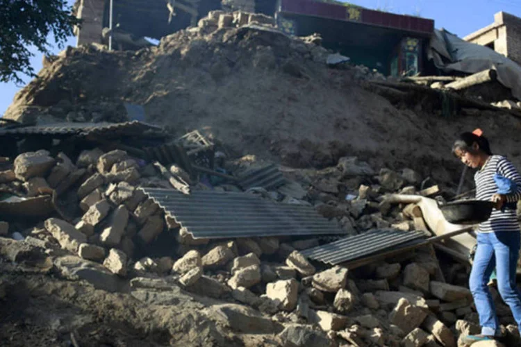 
	Mulher caminha sobre destro&ccedil;os ap&oacute;s terremoto em Gansu, na China: terremoto de 6,6 graus Richter em Gansu, na China, deixa 95 mortos, 1.001 feridos, 226.700 evacuados e derruba 51.800 casas
 (China Daily/Reuters)