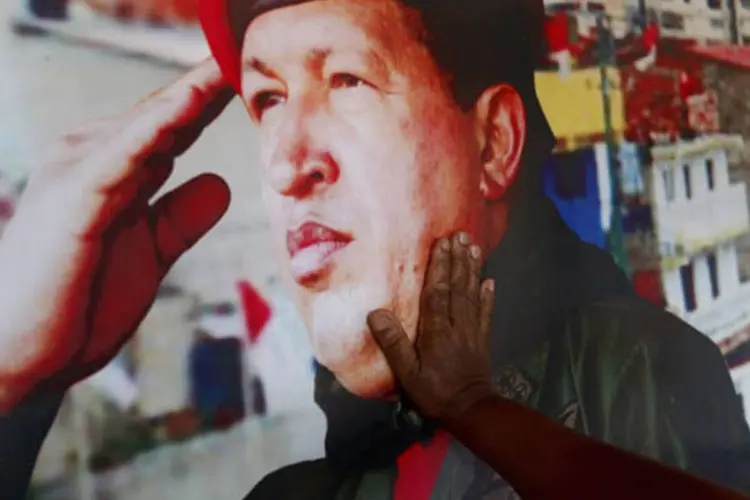 Mulher toca a fotografia de Hugo Chávez: homenagens foram lideradas pelo atual presidente Nicolás Maduro, que lembrou do ex-presidente, a quem chama de "meu pai político" no Twitter (REUTERS/Jorge Silva/Reuters)