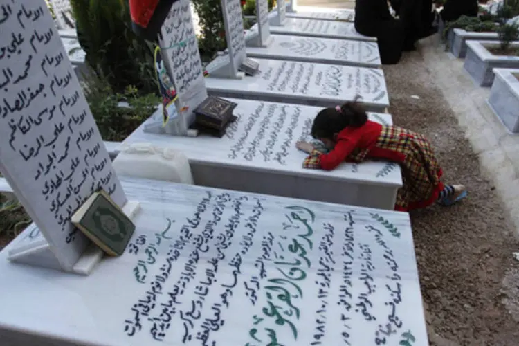 Parentes visitam túmulos em cemitério de combatentes xiitas na área de Sayeda Zainab: conflito já custou mais de 100 mil vidas (Alaa Al-Marjani/Reuters)