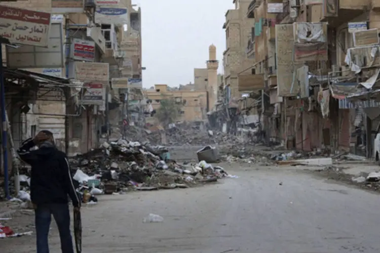 Membro do exército livre da Síria caminha em uma rua com prédios destruídos em Deir al-Zor (Khalil Ashawi/Reuters)