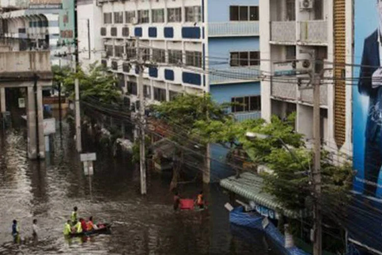Moradores tentam atravessar as ruas alagadas perto do rio Chao Praya em Bangcoc: enchentes deixaram ao menos 381 mortos e 2,5 milhões de vítimas (Nicolas Asfouri/AFP)