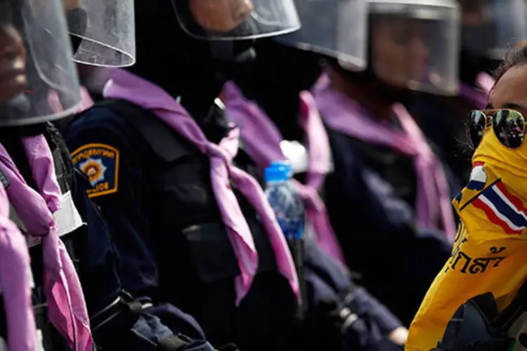 Manifestante olha para policiais na Tailândia: os manifestantes abandonaram a área e se reagruparam em outro local antes de a polícia chegar (REUTERS/Damir Sagolj)