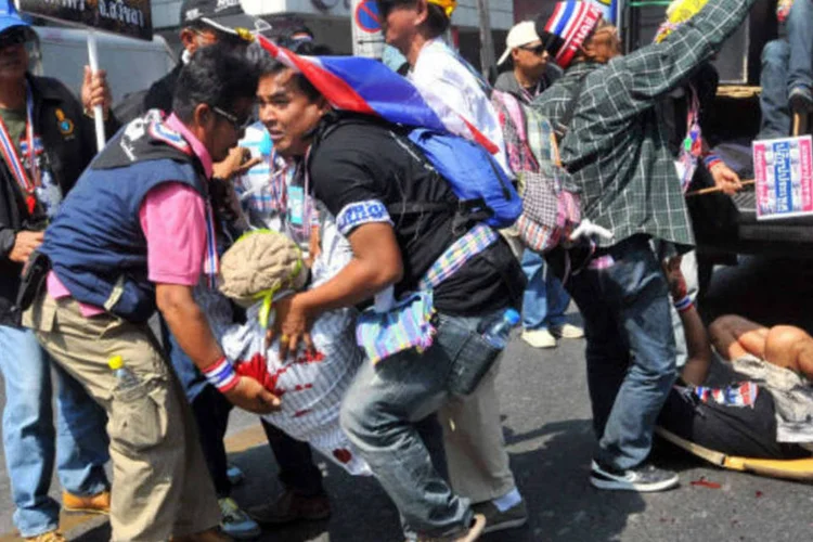 Manifestantes contrários ao governo ajudam a carregar homem ferido por uma explosão durante um protesto em Bangcoc (REUTERS/Stringer)