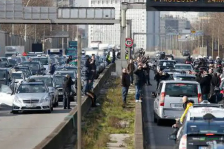 Taxistas bloqueiam uma estrada de Paris: veículos de turismo com chofer podem ser reservados por telefone e, teoricamente, não pegam passageiros na rua (Thomas Samson/AFP)