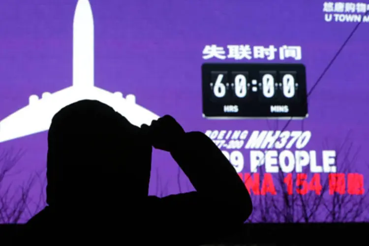 Mulher olha uma tela que mostra o número de horas que o voo MH370 da Malaysia Airlines está desaparecido, e o número pessoas que estavam no avião, em Pequim (Jason Lee/Reuters)
