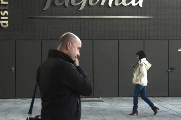 
	Pedestres usam seus celulares enquanto passam pela sede da Telef&oacute;nica
 (Angel Navarrete/Bloomberg)